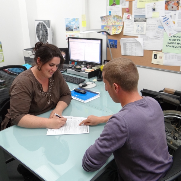 Une femme du Relais Handicap parle avec un étudiant dans un bureau