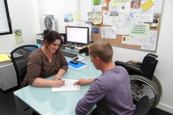 Une femme du Relais Handicap parle avec un étudiant dans un bureau