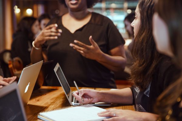 Une femme qui parle devant deux autres femmes pour approfondir son français